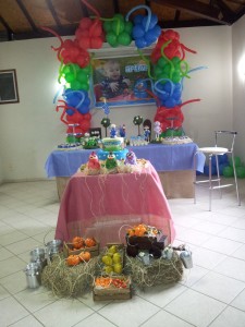 Mesa de bolo e mesa de doces ao fundo